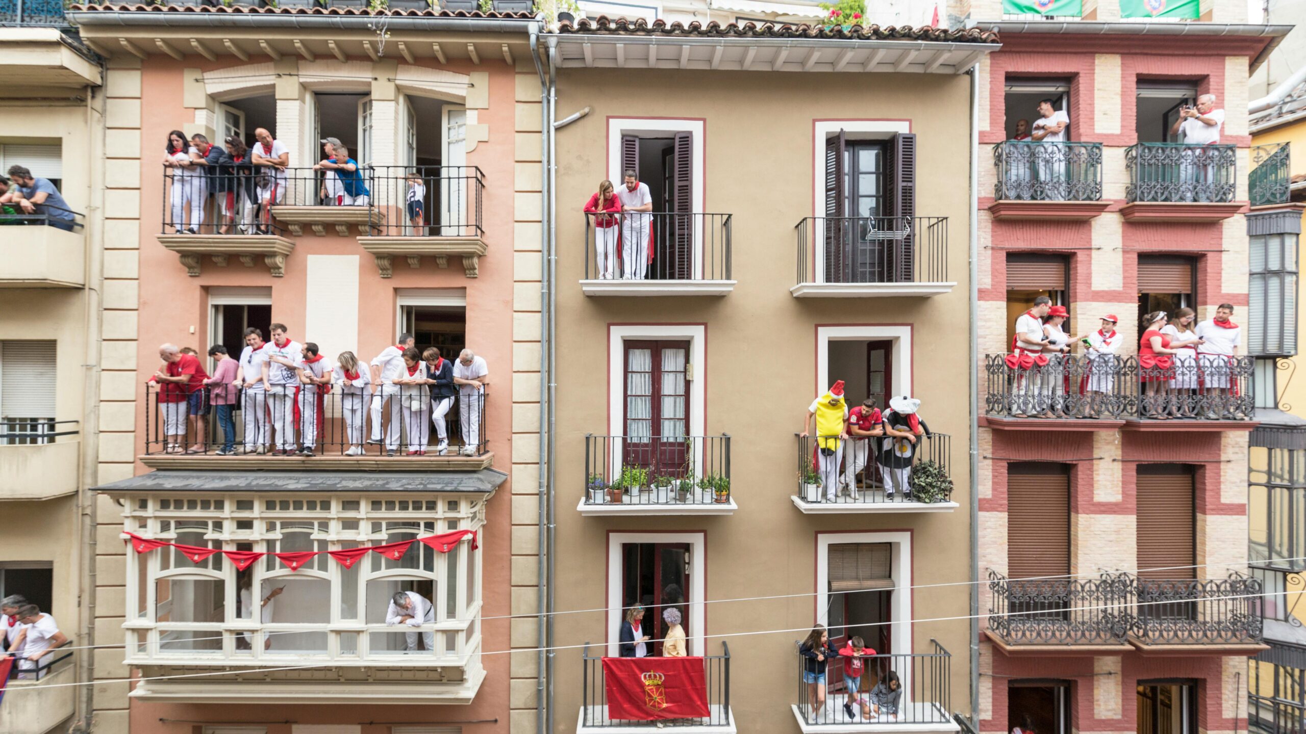 People watching a city festival from balconies showcasing urban community life in daylight.